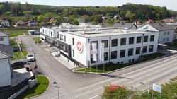 Moderne Gebäude mit Logo und Flaggen, umgeben von Grünflächen.