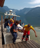 Rettungskräfte laden eine verletzte Person von einem Boot ins Wasser.