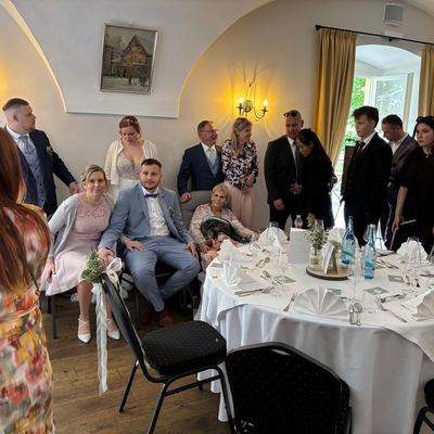 Hochzeitsfeier mit Brautpaar, Gästen und festlich gedecktem Tisch.