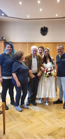 Eine Braut in Weiß steht mit sechsmal Begleiter in einem Raum.