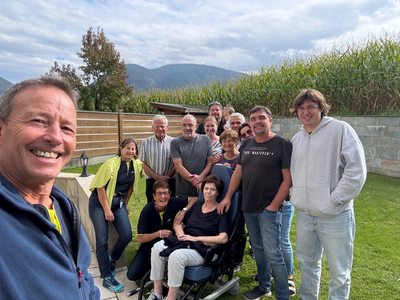 Gruppe von Personen, die gemeinsam im Freien posieren, lächelnd und freundlich.