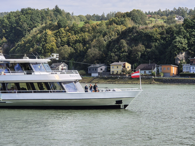 Ein Ausflugsschiff fährt auf einem ruhigen Wasserweg vorbei an Uferhäusern.