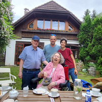Familie posiert lächelnd im Garten vor einem Haus.