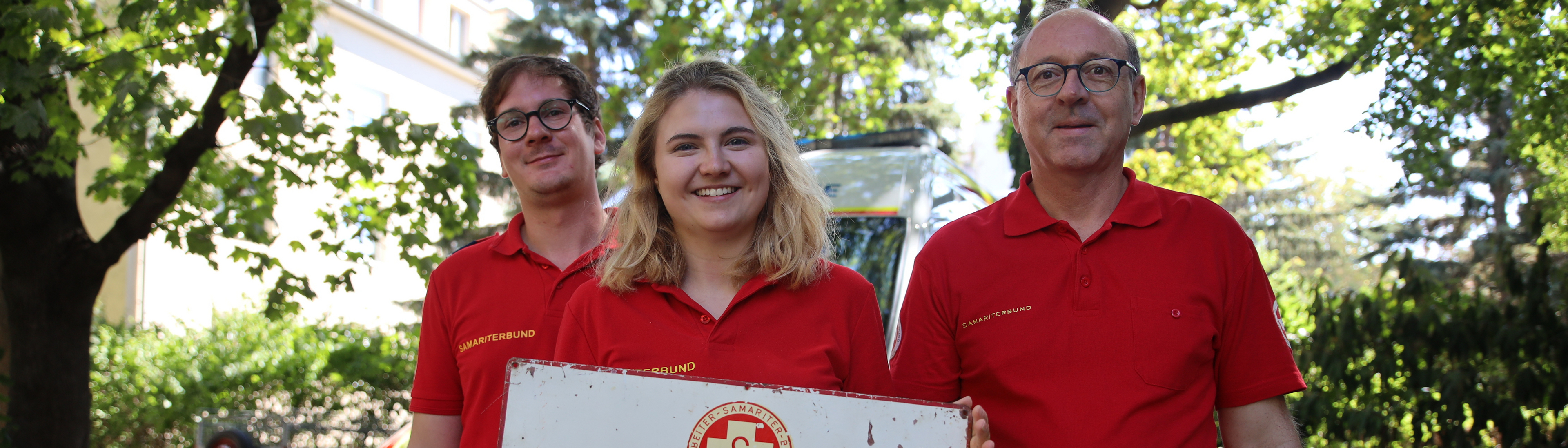3 Samariter:innen mit Vintage-Hinweisschild 