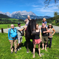 Sonja auf Pferd sitzend, umgeben von unserem Team und ihren Liebsten